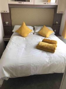 uma grande cama branca com almofadas amarelas em Stunning LAKE SIDE Caravan with HOT TUB at Tattershall Lakes em Tattershall