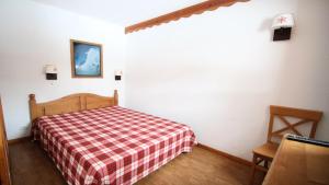 una camera con un letto con una coperta a quadri rossa e bianca di Résidence Parc Aux Etoiles - C104PAE - APPARTEMENT 2 CHAMBRES AVEC BALCON MAE-8824 a Narreyroux