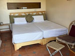 a bedroom with a large bed with white sheets and a chair at Gite & Camping route Ouarzazate in Chouiter