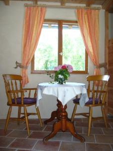 uma mesa com duas cadeiras e um vaso de flores sobre ela em Gite de Mailhac em Loubières