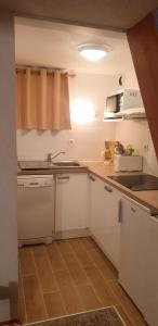 une cuisine avec des armoires blanches et un évier dans l'établissement Résidence Les Arolles - LES AROLLES - AR17A MAE-3149, à Villarodin-Bourget