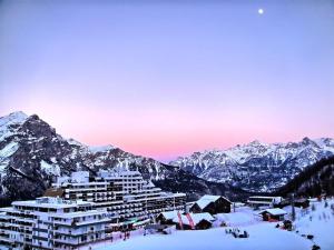 un edificio en la nieve con montañas en el fondo en Résidence Valgardena - Appartements pour 4 Personnes 864 en Les Prés