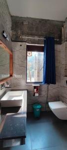 a bathroom with a sink and a toilet and a window at Camp Hornbill Corbett in Rāmnagar