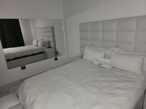 uma cama branca num quarto com um espelho em Sirwine Hotel, Bar and Restuarant em Windhoek