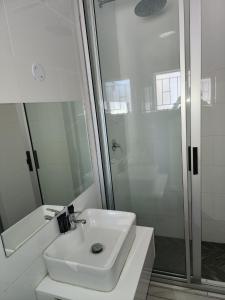 uma casa de banho branca com um lavatório e um chuveiro em Sirwine Hotel, Bar and Restuarant em Windhoek