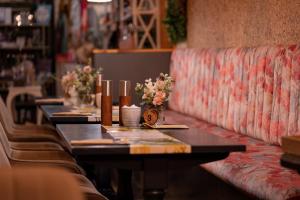 a row of tables in a restaurant with flowers on them at The Hive at Poppi-Red in Hawkshead