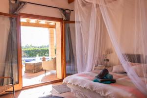 a bedroom with a bed with a mosquito net at Natursteinfinca mit Meerblick & Pool in Porto Cristo