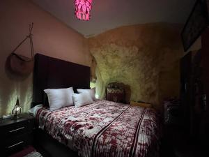 1 dormitorio con cama y luz rosa en Grotte Thami en Bhalil