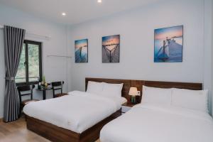 two beds in a room with white walls at Napoli Hostel in Cat Ba