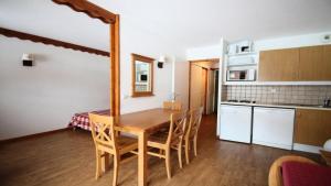 eine Küche und ein Esszimmer mit einem Tisch und Stühlen in der Unterkunft Résidence Parc Aux Etoiles - Appartements pour 6 Personnes 064 in Narreyroux