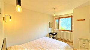 a bedroom with a bed and a desk and a window at Le Chalet - Appartements pour 6 Personnes 104 in Puy-Saint-Vincent