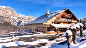 a house in the snow with mountains in the background at Le Chalet - Appartements pour 6 Personnes 104 in Puy-Saint-Vincent
