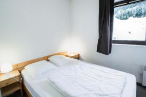 uma cama branca num quarto com uma janela em Résidence Les Portes De La Vanoise - 2 Pièces pour 6 Personnes 193184 em Villarodin-Bourget
