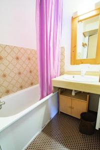 uma casa de banho com uma banheira, um lavatório e um espelho. em Résidence Les Portes De La Vanoise - 2 Pièces pour 6 Personnes 193184 em Villarodin-Bourget