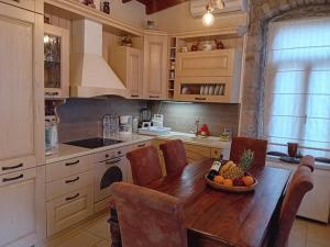 a kitchen with a wooden table with chairs and a bowl of fruit at Ignatia's house in Polichnítos