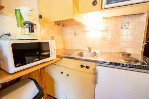 Il comprend une petite cuisine équipée d'un four micro-ondes et d'un évier. dans l'établissement Résidence Le Tetras - Studio pour 4 Personnes 193156, à Villarodin-Bourget