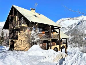 una cabaña de madera en la nieve con una montaña en Résidence Les Soldanelles - Appartements pour 6 Personnes 134 en Puy-Saint-Vincent