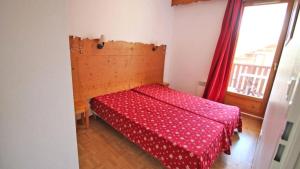 Un dormitorio con una cama con una colcha roja y una ventana en Résidence Les Gentianes - Appartements pour 6 Personnes 954, en Narreyroux