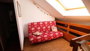 un divano rosso seduto nell'angolo di una stanza di Résidence Parc Aux Etoiles - A205PAE - APPARTEMENT DUPLEX 2 CHAMBRES, BALCON MAE-8964 a Narreyroux Altre 2 foto