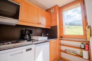 a kitchen with wooden cabinets and a window at PIERRAFORT G - Appartement PIERRAFORT 19 pour 5 Personnes 20 in Valmorel