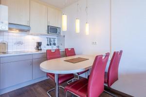 a kitchen with a table and red chairs in a room at Haus Atlantic, FeWo 605 in Döse