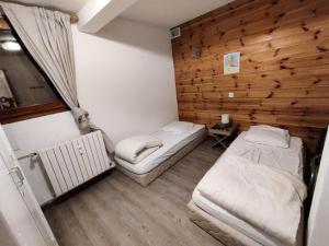 two beds in a room with a wooden wall at Le Chalet - Appartements pour 4 Personnes 174 in Puy-Saint-Vincent