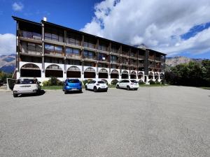 un grande edificio con auto parcheggiate in un parcheggio di Résidence Saint Roch - Agréable Studio 4 Personnes à proximité des pistes+Coin cabine MAE-8044 a Puy-Saint-Vincent