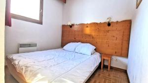 un letto in una camera con testiera in legno di Résidence Les Gentianes - Appartements pour 6 Personnes 204 a Narreyroux