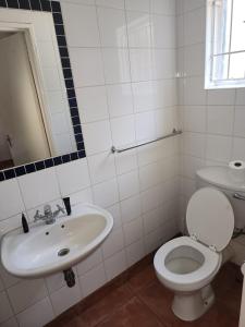 a white bathroom with a toilet and a sink at Sirwine Hotel, Bar and Restuarant in Windhoek