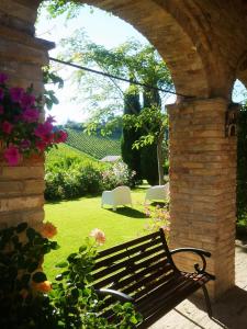 un banco del parque sentado bajo un arco en un jardín en Agriturismo Fiorano, en Cossignano
