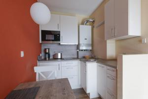 uma cozinha com armários brancos e uma mesa de madeira em Haus Atlantic, FeWo 513 em Döse