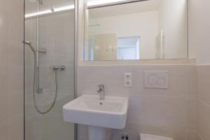 uma casa de banho com um lavatório e um chuveiro com um espelho. em Haus Atlantic, FeWo 513 em Döse