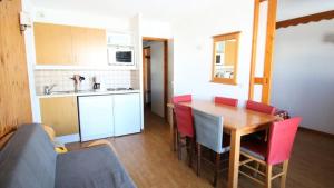 una cucina con un tavolo di legno e sedie rosse di Résidence Parc Aux Etoiles - PARC AUX ETOILES -C314- AVEC PISCINE ET SAUNA-Appt 4/6 p MAE-8404 a Narreyroux