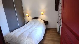 białe łóżko w małym pokoju z 2 światłami w obiekcie Résidence Le Palatin - Appartements pour 6 Personnes 484 w mieście Pelvoux