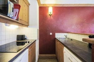 a kitchen with a sink and a red wall at Quartier La Forêt - maeva Home - Appartement 2 pièces 6 personnes + coin cabine - Sélection MAE-1634 in Valmorel +23 photos