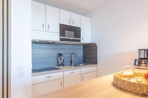 eine Küche mit weißen Schränken, einer Spüle und einer Mikrowelle in der Unterkunft Haus Nautic, FeWo 115 in Döse