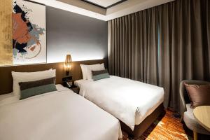 una habitación de hotel con 2 camas y una silla en Solaria Nishitetsu Hotel Taipei Ximen en Taipéi