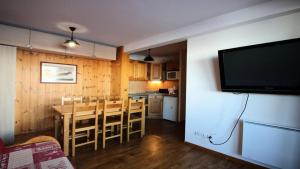 a kitchen and dining room with a table and a television at Résidence Dame Blanche - Chalets pour 6 Personnes 721 in Narreyroux