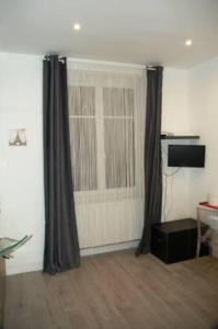 a living room with curtains and a table and a desk at Lovely studio in Paris in Paris