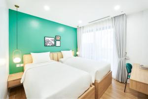 two beds in a room with a blue wall at Wilque Hotel Hanoi in Hanoi