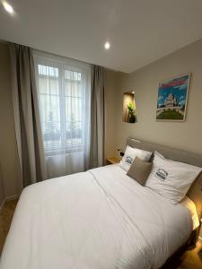 a bedroom with a large white bed with a window at Les Chambres du Faubourg in Paris