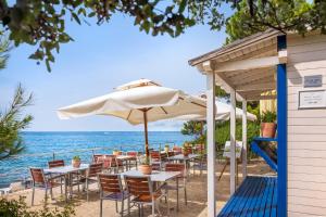 a restaurant on the beach with tables and an umbrella at Maistra Camping Koversada Uncovered Naturist Pitches in Vrsar