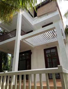 Dieses weiße Haus verfügt über eine Veranda und einen Balkon. in der Unterkunft Dinuri villa in Tangalle
