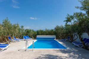 a swimming pool with blue chairs and a bunch at Holiday Home Malačnica in Supetar
