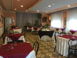 Hotel Magda في Novafeltria: قاعة احتفالات مع طاولات وكراسي مع مفارش مائدة حمراء وبيضاء