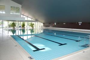 a large swimming pool with blue water in a building at Wiet Kieker - mit bestem Meerblick in Sierksdorf