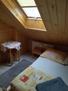- une chambre mansardée avec un lit et une table dans l'établissement Nad Grapą, à Gliczarów