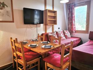 a room with a table with chairs and a television at Résidence Terrasse - La Terrasse 11 - Joli appartement, skis aux pieds MAE-5054 in Valmorel