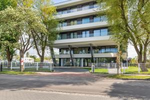 um edifício com uma cerca e árvores em frente em Unique Baltic Marina Residence with Sauna & Fitness by Renters em Kolobrzeg