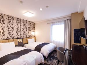 um quarto de hotel com duas camas e uma janela em APA Hotel STAY Toyama em Toyama